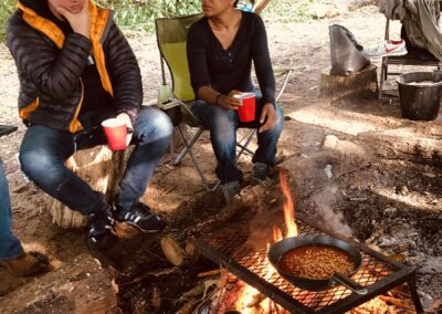 two adults cooking beans on campfire