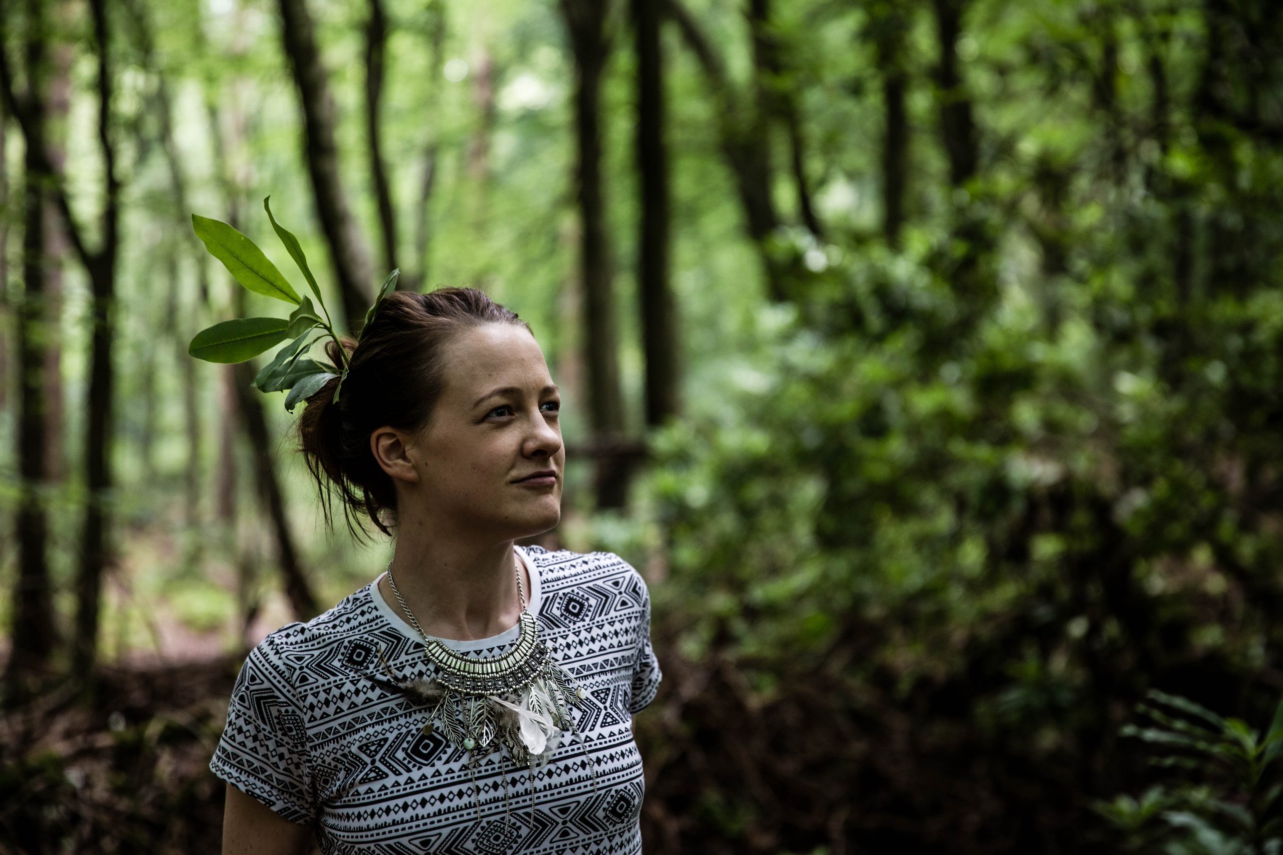 close up of woman with leaves in hair in the woods