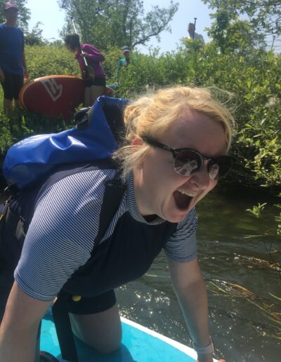 close up of woman laughing and crouching on SUP paddleboard on River Wey